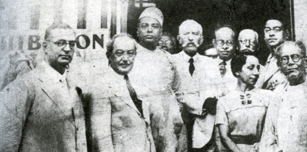 A group of men and a woman on the right pose for a photograph outside the Indian School of Oriental Art.