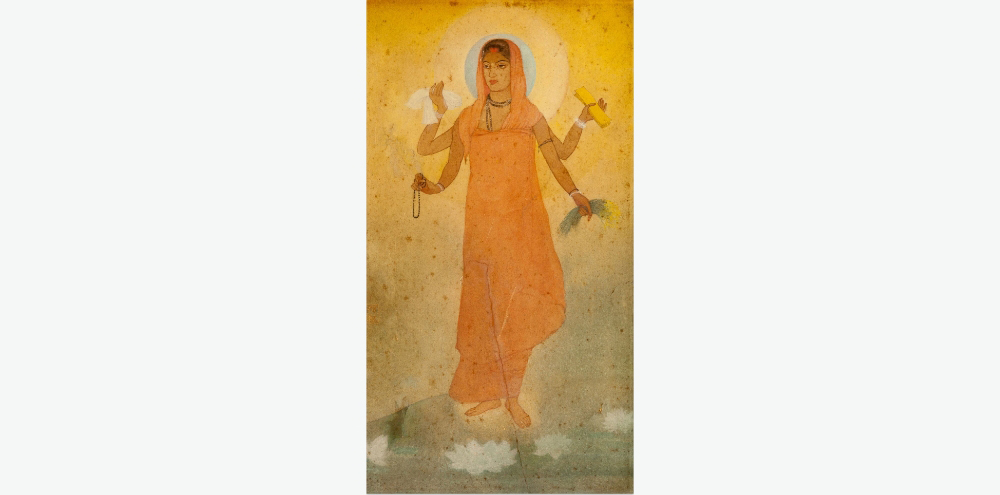 A four-armed female figure with a halo is clad in a saffron garment and stands against a hazy background with three white lotuses at her feet. Her arms hold a white cloth, rosary beads, a manuscript and paddy sheaves.