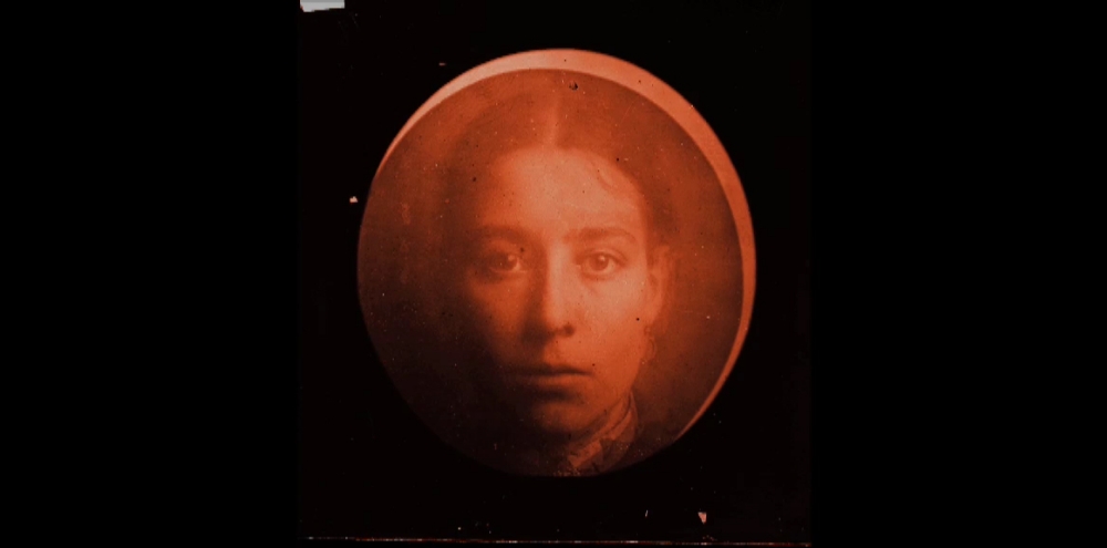 A film screengrab featuring a headshot of a woman staring at the camera superimposed on a red ball.