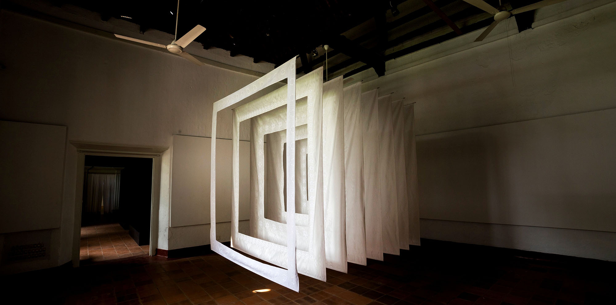 Multiple cut-out cloth screens are installed in descending order of thickness one after another in a large room.