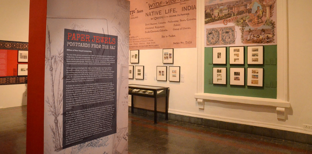 An exhibition space with framed postcards and illustrated banners on the walls.